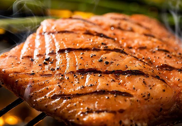 Wild King Salmon with char marks cooking on an outdoor grill