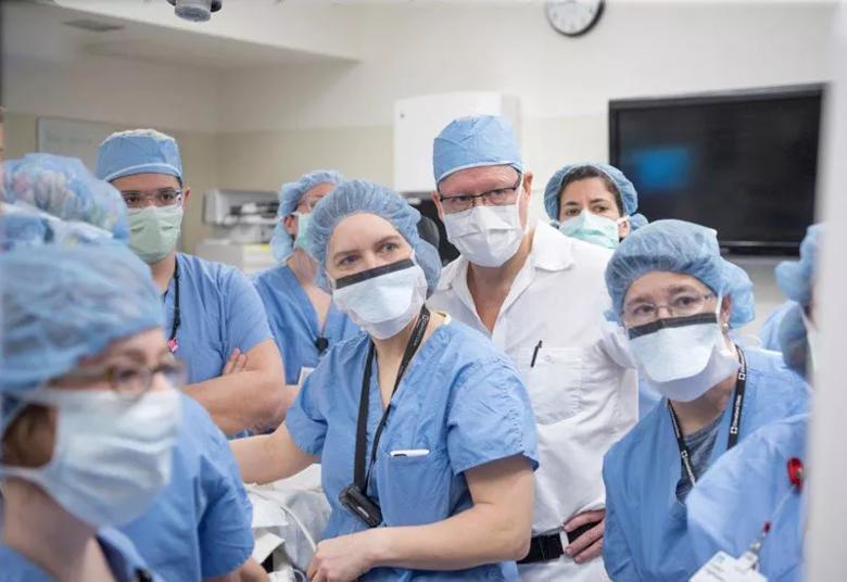 Surgical team members study an ultrasound monitor as they prepare to begin the operation..