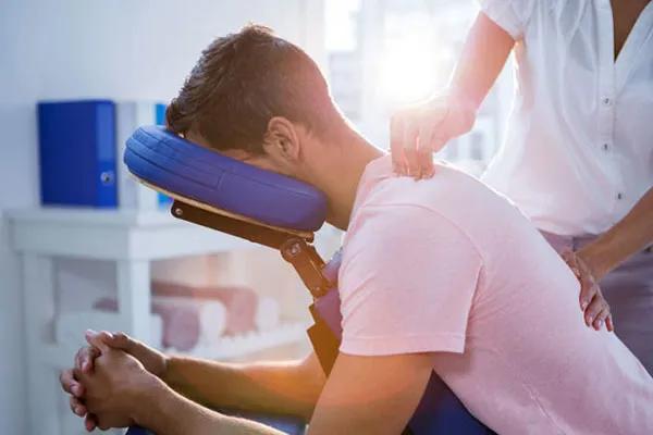 Patient leaning forward to receive a therapeutic neck massage.