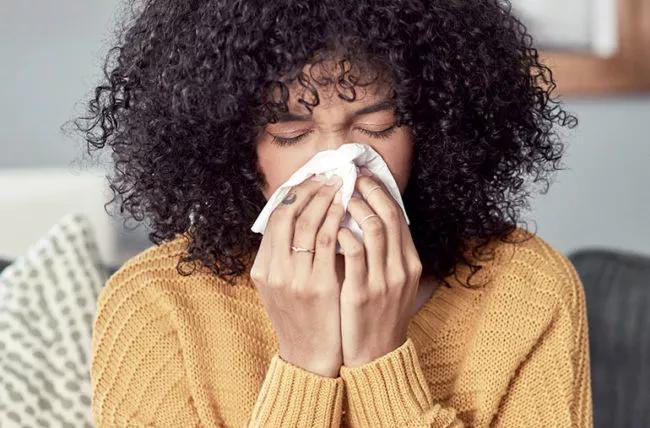 Person blowing nose into a tissue