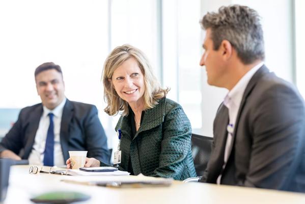 Sonja O'Malley speaking with two people in a conference room.