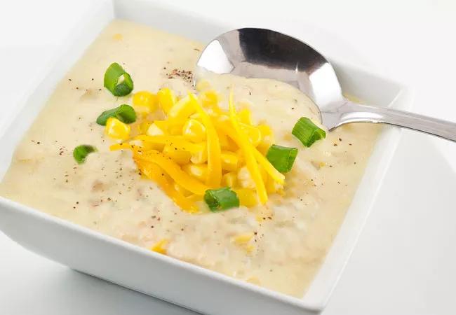 Creamy corn soup in bowl, with cheddar cheese on top