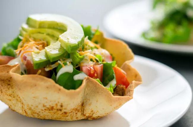 Taco salad in taco bowl, with avocado on top