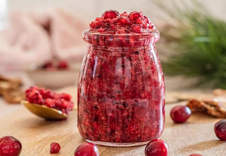 A clear jar of dark-red pomegranate citrus cranberry relish