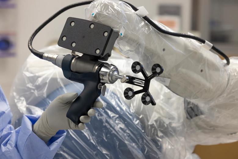 Surgeon's hand holding the robotic arm