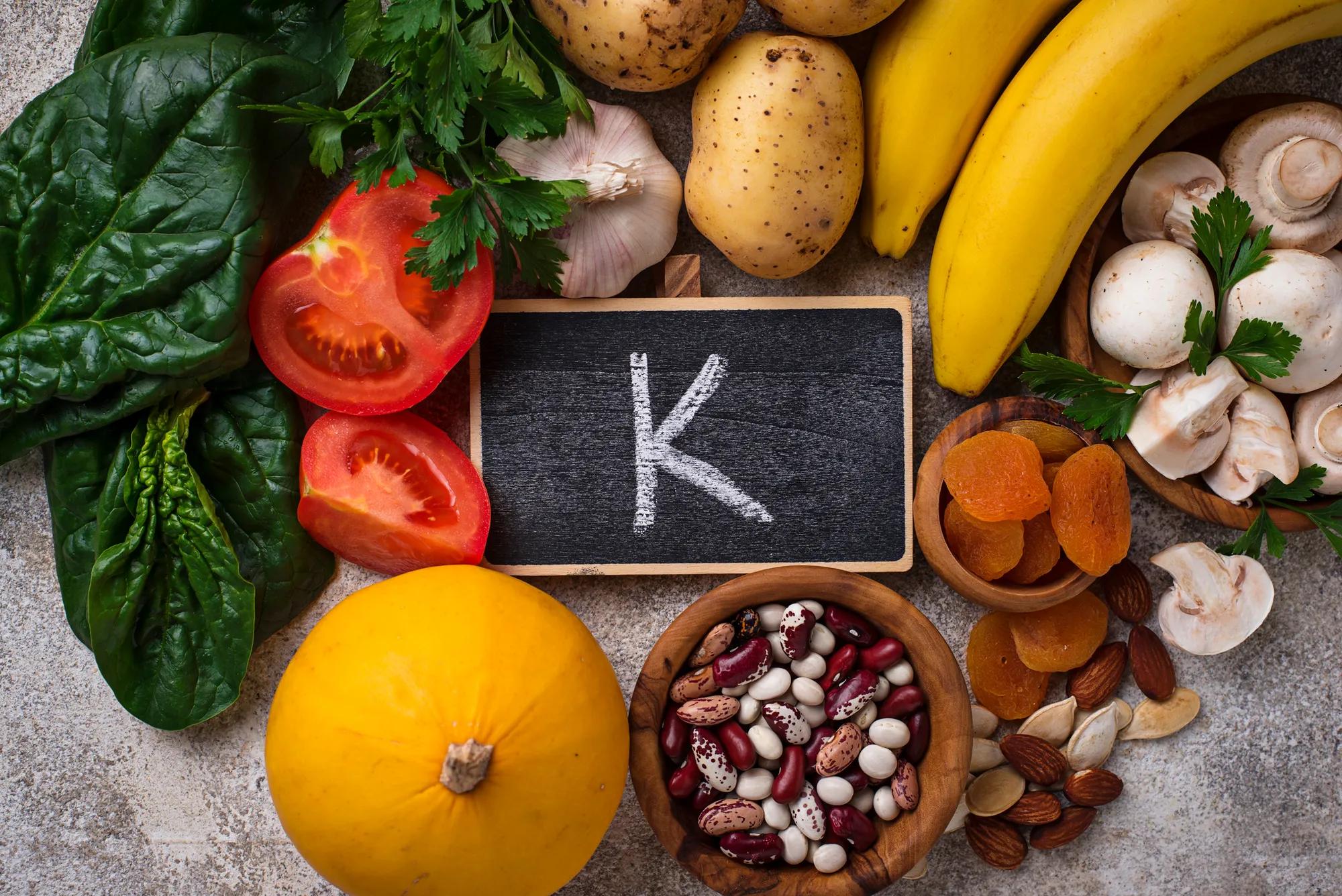 Assortment of potassium-rich foods including bananas, potatoes, spinach, avocados, beans, and oranges