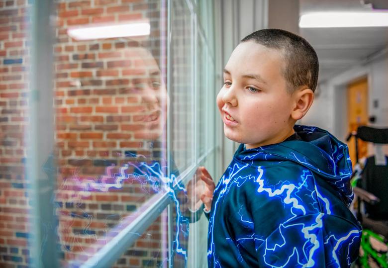 A child smiles at his reflection in a window