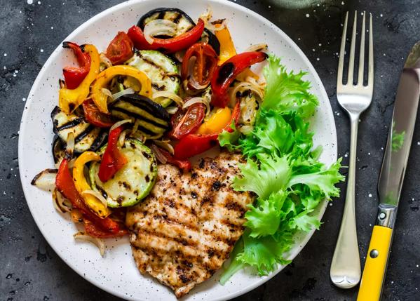 Grilled pork fillet, roasted vegetables and glass of wine on a dark background, top view. Delicious  food