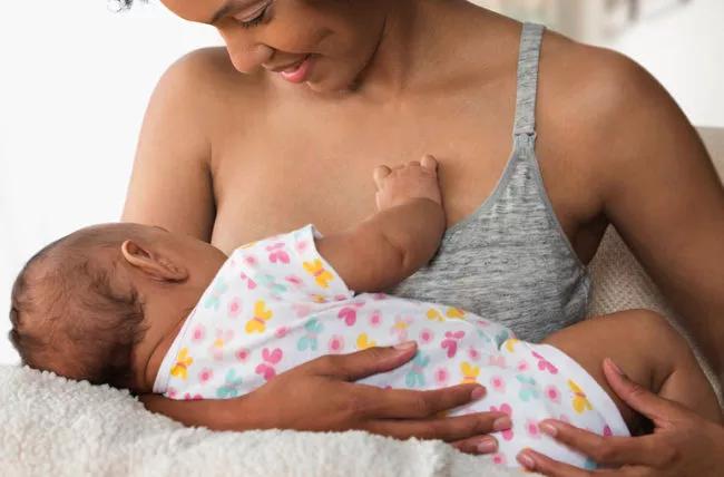 Smiling mother breastfeeding (chestfeeding)