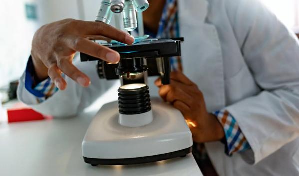 Forensic scientist looking through microscope while working on research in a laboratory