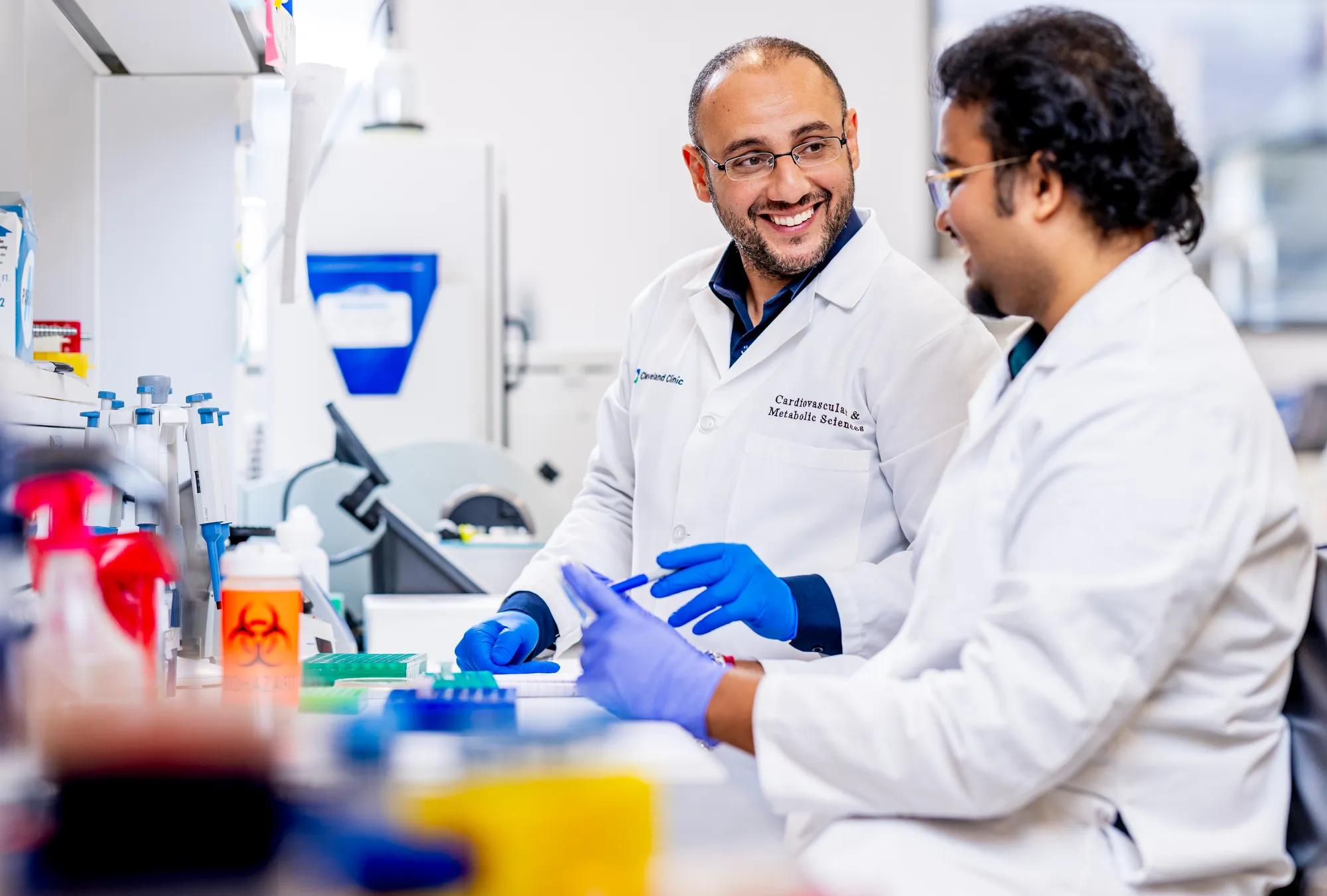 Researchers in a lab working with testing equipment while wearing protective gear.