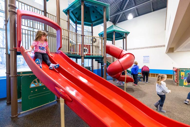 A child sits at the top of a red slide