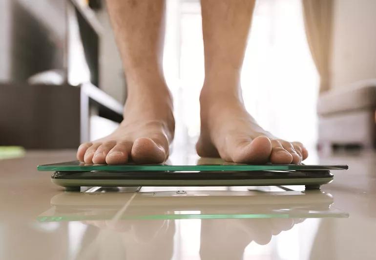 adult stepping on a BMI scale