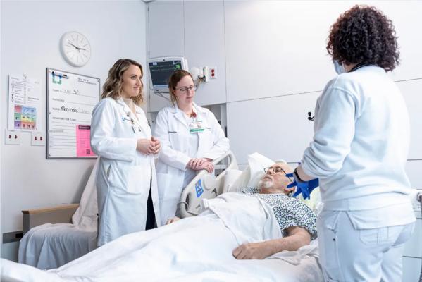 Nurses discuss care with patient.