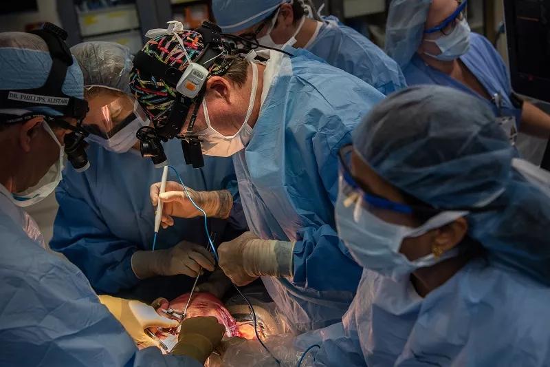 Dr. Phillips offers guidance as Dr. Cass begins to exteriorize the lung mass.