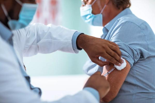 Mature man taking a vaccine from his doctor