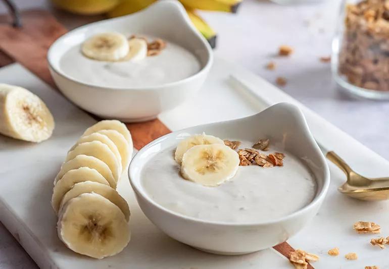 two bowls of banana mouse on a tray with slices of banana