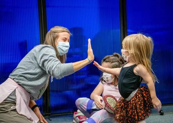 Woman high-fiving little girl in a dance costume