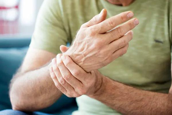 Close-up of a man holding his wrist.