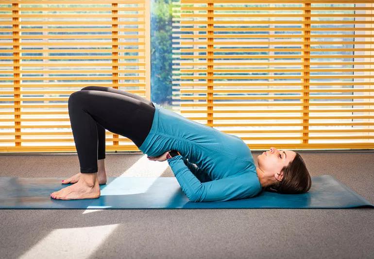 person on yoga mat in supported bridge pose