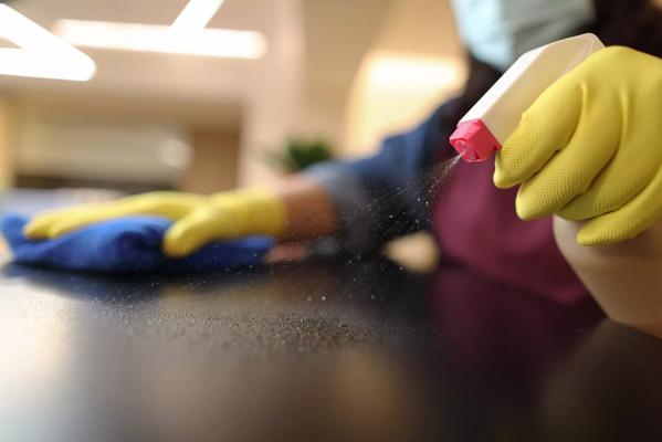 Woman wearing gloves cleaning desktop