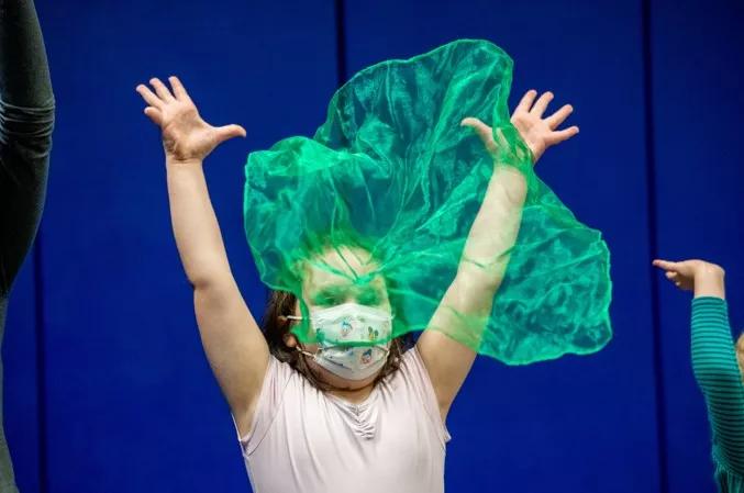 Person throwing green scarf in air