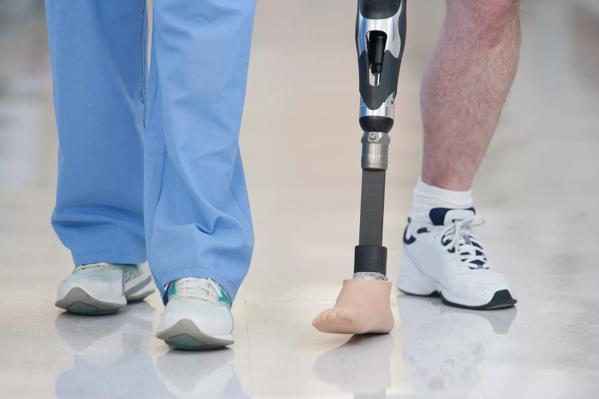 healthcare worker walking with man with leg prosthesis