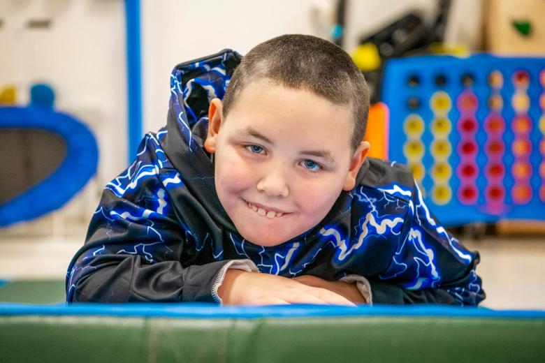 A child smiles while crawling on a green mat