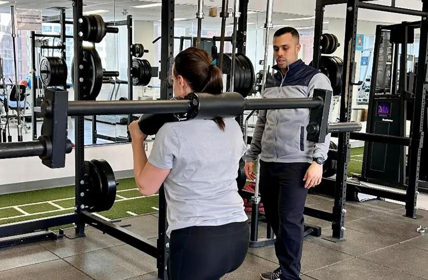 Person lifting weights under a caregiver's supervision.