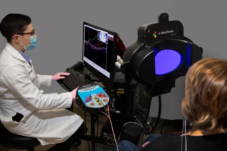 The patient looks at a purple screen while the doctor sits at a nearby computer