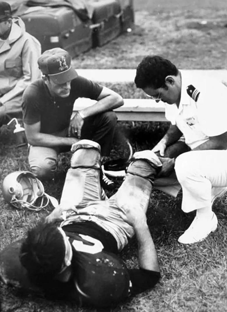 Dr. Bergfeld examines a football player with a knee injury