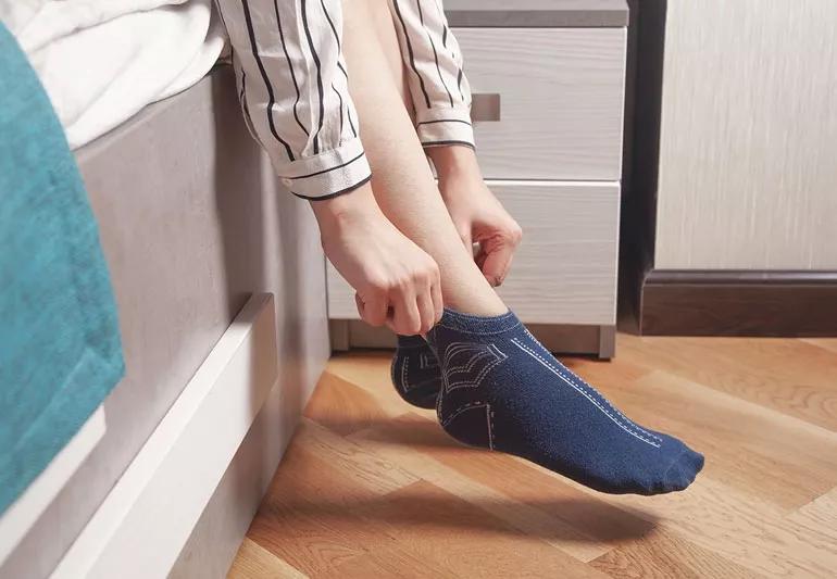 A young boy wearing socks and lying down on a wooden floor Stock