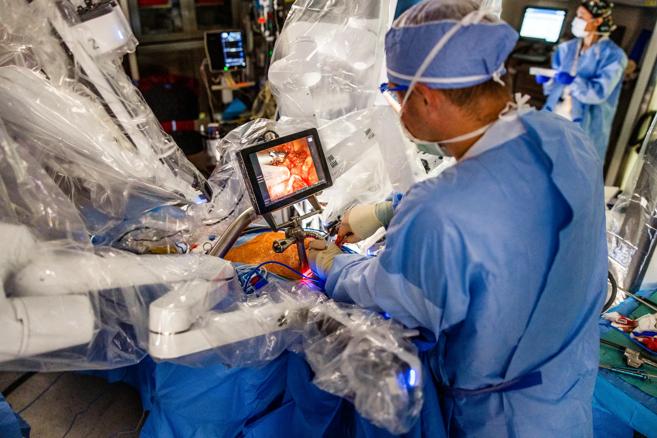 surgeon looking at small monitor at operating table during surgery