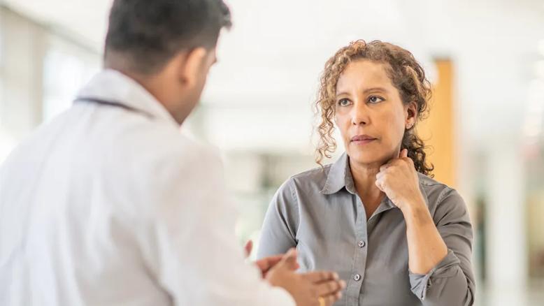woman looking concerned as she listens to a doctor speak to her