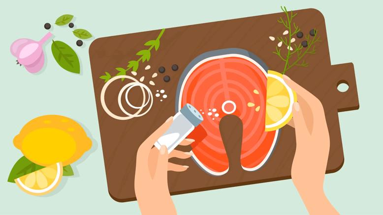 Hands prepping salmon with lemon and spices