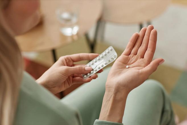 Woman holding birth control pill