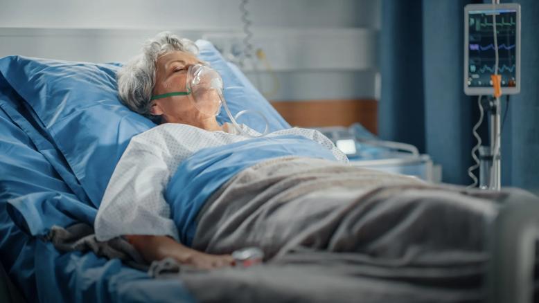 Older woman in hospital bed with oxygen mask