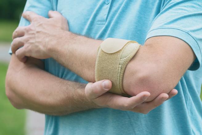 Person holding their elbow that has a brace on it