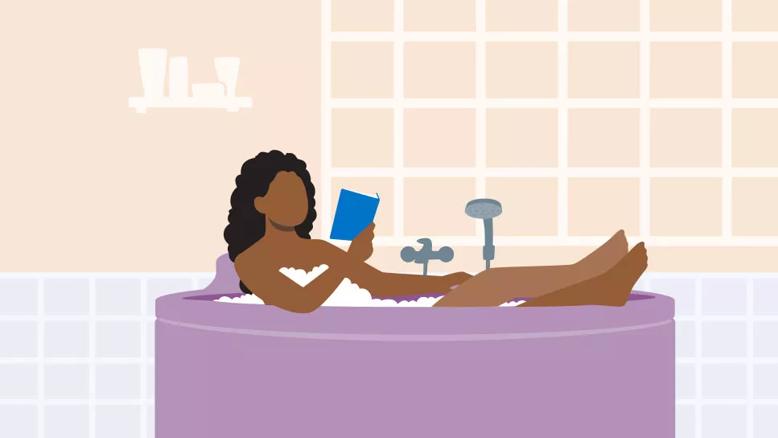 Person relaxing in bubble bath, reading a book
