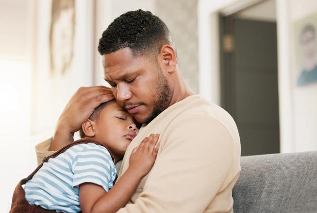 Dad holds sick child on sofa