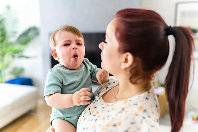 Caregiver holding sick, coughing baby