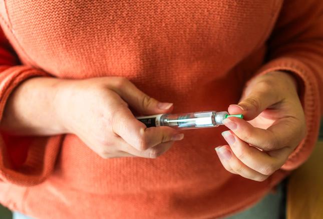female hands holding a pharmaceutical injector