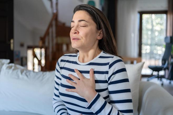 Woman sitting with hand on chest, taking deep breaths