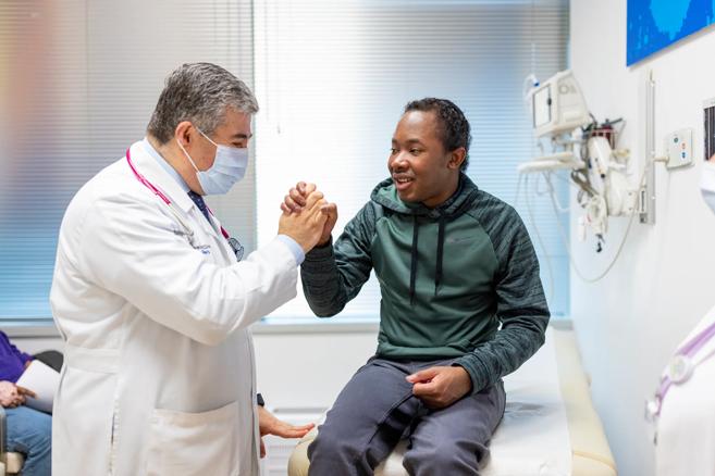 Doctor in a white coat holding hand of a patient in a clinic room