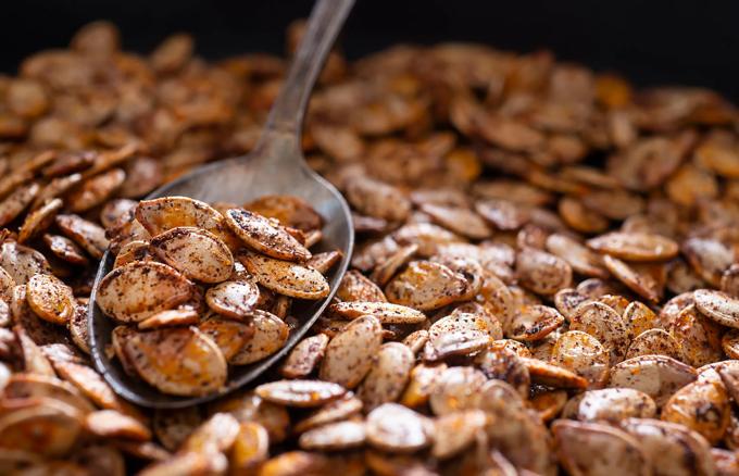 Spoonful of pumpkin seeds on a bed of roasted pumpkin seeds