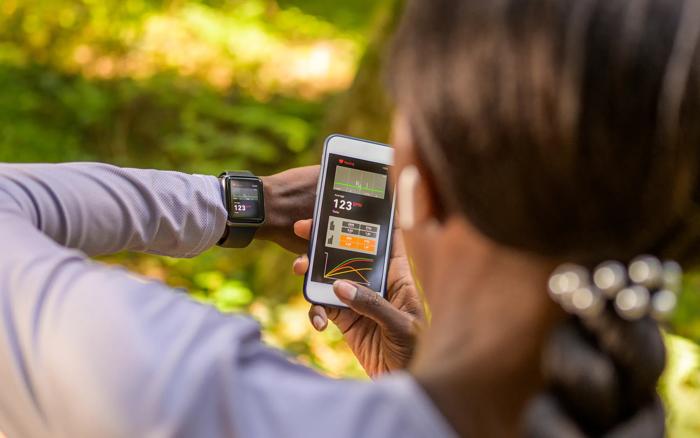 Person checking their fitness tracker on their phone and smartwatch