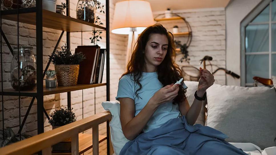 female on couch reading a nasal spray bottle label