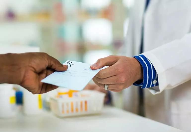 Person handing a pharmacist a prescription.