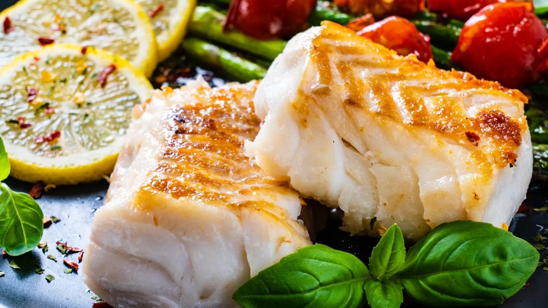 A plate of baked cod and vegetables