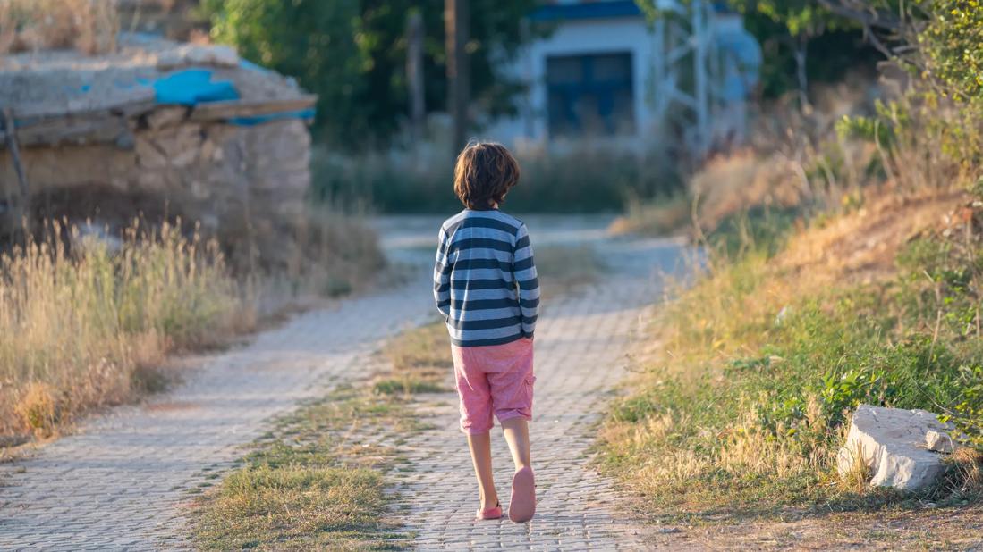 Young boy wandering alone down a roadway